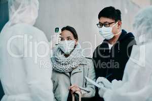 Traveling couple getting a covid temperature scan at the border with medical security doing screening test for safety during pandemic. Foreign people or traveler arriving at an airport with face mask