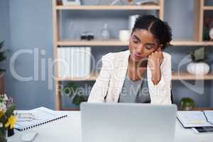 Already on her way to dreamland. a young businesswoman looking tired while using a laptop at her desk in a modern office.