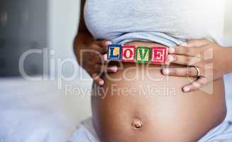 Made with love. a pregnant woman with wooden blocks on her belly that spell the word love.