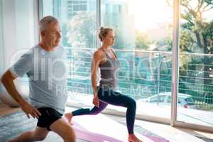 Stretch properly, avoid injury. a mature couple stretching on yoga mats before working out at home.