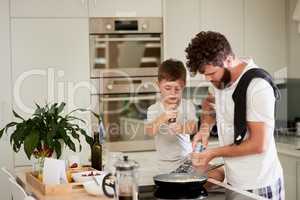 Master chefs in the making. an adorable little boy and his father making breakfast together at home.
