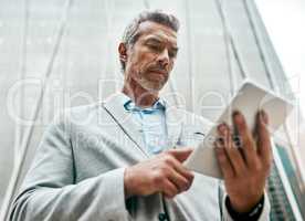 Smart businesspeople know how to make smart moves. a mature businessman using a digital tablet in the city.