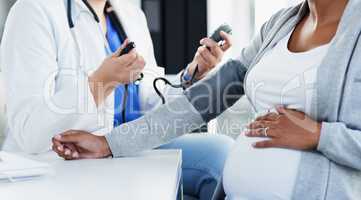 Your blood pressure will tell us a lot. an unrecognizable female doctor checking the blood pressure of a pregnant patient at a hospital during the day.