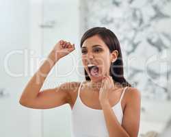 Open wide and clean all those hard to reach places. an attractive young woman flossing her teeth in the bathroom.