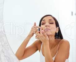 This is going to ruin my day if it stays. an attractive young woman squeezing a pimple on her face in the bathroom.