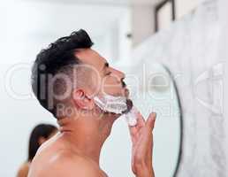 Its all coming off. a handsome young man applying shaving cream to his face in the bathroom.