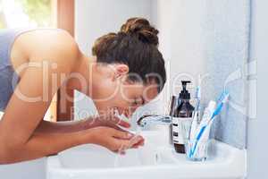 Skincare is a daily commitment. an attractive young woman washing her face in the bathroom.