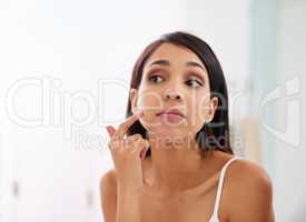 Your skin needs all the hydration it can get. an attractive young woman applying moisturizer to her face in the bathroom.