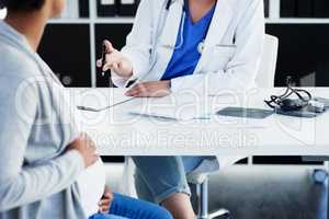 Let me explain. an unrecognizable female doctor consulting with a pregnant patient at a hospital during the day.