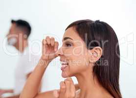 Freshening up for a beautiful day. an attractive young woman flossing her teeth in the bathroom.