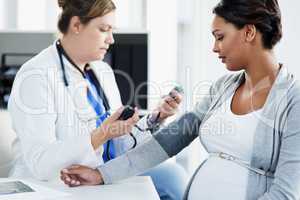 Lets check your blood pressure. a confident female doctor checking the blood pressure of a pregnant patient at a hospital during the day.