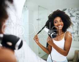 Loving care nourishes luxurious hair. an attractive young woman blowdrying her hair at home.