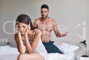 I dont want to hear anymore. a husband arguing while his wife covers her ears in their bedroom at home.