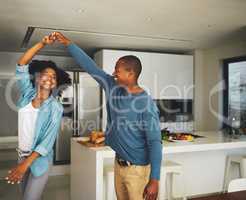 Spinning around. a cheerful young couple dancing together in the kitchen at home during the day.