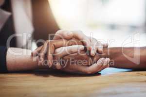 Support, compassion and trust while holding hands and sitting together at a table. Closeup of a loving, caring and interracial couple or friends comforting each other after a loss or cancer news