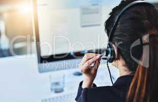 Please hold while I work on resolving the issue. Rearview shot of a young woman working in a call centre.