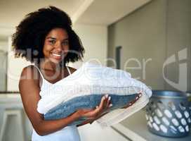 Neat and in order is how I like it. an attractive young woman holding folded towels at home.