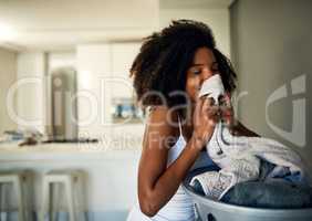 I can smell the freshness. an attractive young woman smelling clean laundry at home.