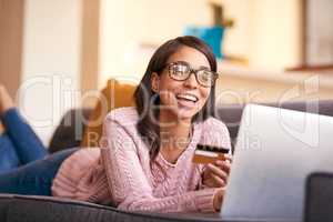 Retail therapy is even better when youre relaxing. an attractive young woman using a laptop and credit card on the sofa at home.