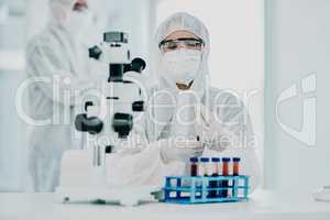 A scientist conducting a medical experiment to research covid vaccine in a lab and collecting blood samples. Healthcare researcher analyzing chemicals in a chemistry laboratory wearing a hazmat suit