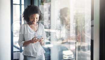 Keeping a close connection to all her clients. a young businesswoman using a cellphone in an office.