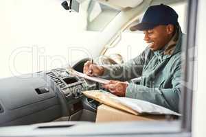 He knows how to run a successful delivery schedule. a courier writing on a clipboard while sitting in a delivery van.