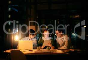 Driving teamwork to the fore in order to stay on schedule. businesspeople working together on a digital tablet in an office at night.