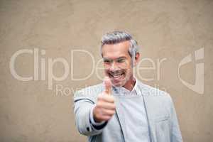 Thumbs up to looking presentable all the time. a smartly dressed mature businessman showing thumbs up outside.