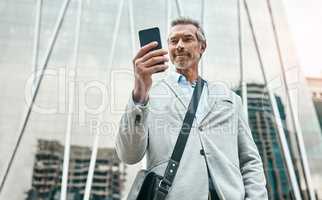 Getting in touch with some business networks. a mature businessman using a cellphone in the city.