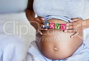 My love grows for you everyday. a pregnant woman with wooden blocks on her belly that spell the word love.