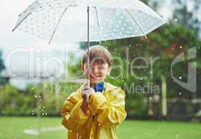Rain never stops him from going outside. Portrait of a cheerful little boy standing with an umbrella outside on a rainy day.