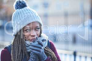 Dressed for warmth when the temperature drops. a beautiful young woman looking thoughtful on a wintery day outdoors.