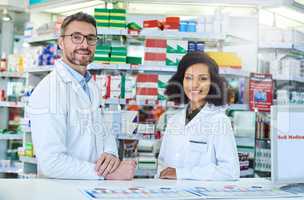 Your friendly neighbourhood pharmacists ready to take care of you. Portrait of a confident mature man and young woman working together in a pharmacy.