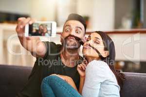 We fell in love with the weird in each other. a young couple taking selfies together at home.