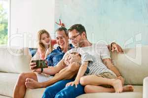 Taking silly selfies on the sofa. an affectionate family of four taking selfies on the sofa at home.