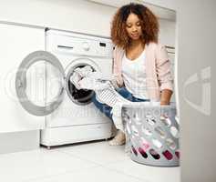 Its chores day time to get busy. a young attractive woman doing laundry at home.