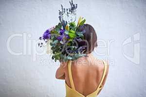 Spring is in the air. Rearview studio shot of an unrecognizable woman holding a bouquet of flowers while standing against a grey background.