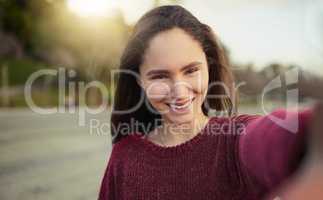 Spending the day just me by myselfie. Portrait of a happy young woman taking a selfie outdoors.