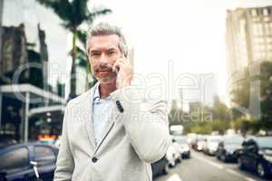 Determination can strike a great deal of success. Portrait of a mature businessman talking on a cellphone in the city.