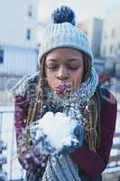 Snow adds that extra sparkle to life. a beautiful young woman blowing a snowball on a wintery day outdoors.