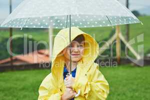 Protected against the weather. Portrait of a cheerful little boy standing with an umbrella outside on a rainy day.
