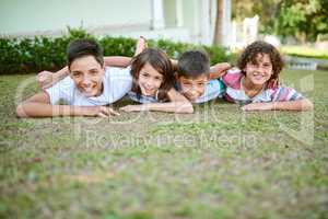 Siblings are one of lifes greatest gifts. Portrait of a group of happy siblings lying together on the grass in their backyard.