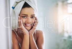 Nourished skin will naturally glow. Portrait of an attractive young woman looking at her face in the bathroom mirror.