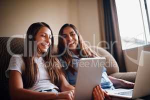 Mom Take a look at this... an attractive mother and her daughter using wireless technology while sitting on the sofa at home.