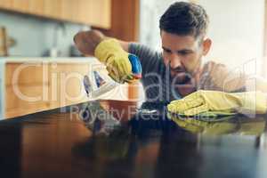 Germs, I will find you and I will eliminate you. a young man cleaning the kitchen counter at home.