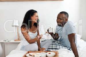 Now that was a satisfying breakfast. a cheerful young couple enjoying breakfast in bed together at home during the day.