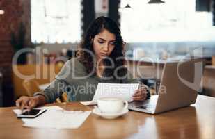 Young businesswoman, entrepreneur and coffee shop owner looking overwhelmed going through paperwork. Serious and concerned female cafe manager going through or reading logistics sheet for the month.