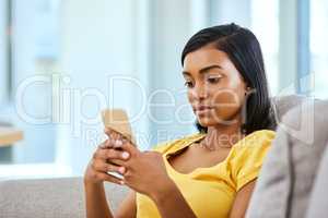 Texting friends and making plans. a teenage girl using a cellphone at home.