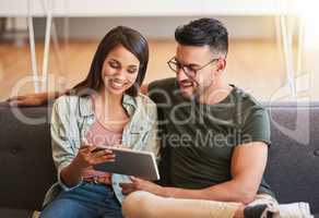 Checkout this new app I downloaded. a young couple using a digital tablet together at home.