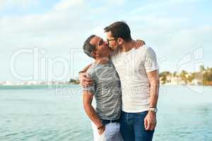 Kisses on the beach is what they live for. an affectionate mature couple spending the day by the beach.